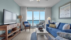 A living room with a television, two chairs, a sofa, and a coffee table. - Calypso 404E, VIP Parking Spot, Beach Chairs! (Panama City Beach)