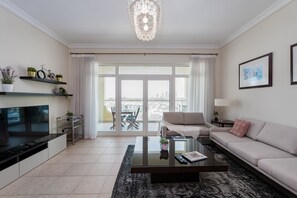 A modern living room with a sofa, coffee table, TV, and a balcony with a city view.