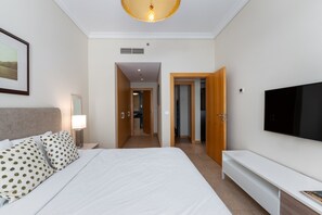 Une chambre d’hôtel comprenant un lit, une télévision, une table de chevet et un couloir menant à d’autres chambres.