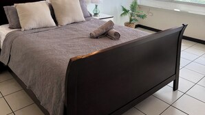 A neatly made bed with a dark headboard, a ceiling fan, a window with a view of buildings, and a wall-mounted air conditioner. - Condado Lagoon View @ Ritz Full Power Generator (San Juan)