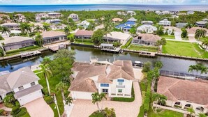 An aerial view of a residential area with houses, a canal, and a dock. - Newly added 5-bedroom house close to Tigertail Beach!! (Marco Island)