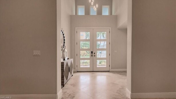 A spacious hallway with a double door leading to a bright room. - Newly added 5-bedroom house close to Tigertail Beach!! (Marco Island)