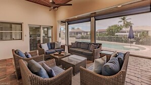 A covered outdoor seating area with wicker furniture and a view of a swimming pool. - Newly added 5-bedroom house close to Tigertail Beach!! (Marco Island)