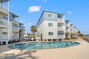 Un hôtel à plusieurs étages doté d’une piscine, de balcons et de palmiers.
