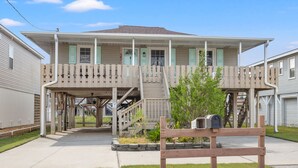 A two-story house with a front porch, a staircase leading to the upper floor, and a mailbox in the front yard. - Escape to Channel Charm: Relaxing Beach Getaway in North Myrtle's Cherry Grove with Scenic Views (North Myrtle Beach)