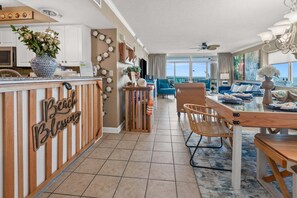 A modern kitchen with a wooden counter, a dining area with a glass table, and a view of the ocean.