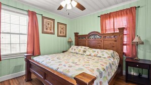 A bedroom with a wooden bed, a nightstand, a lamp, and a ceiling fan. - Escape to Rising Tide: 8-bedroom beach retreat with private pool, hot tub, and modern amenities! (North Myrtle Beach)