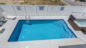 A rectangular swimming pool with a hot tub on one side, surrounded by a white fence with warning signs. - Escape to Rising Tide: 8-bedroom beach retreat with private pool, hot tub, and modern amenities! (North Myrtle Beach)