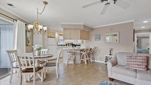 A spacious living area with a dining table, chairs, a sofa, and a kitchen in the background.
