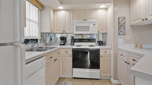 A modern kitchen with white cabinets, a built-in microwave, a stove, and a dishwasher.