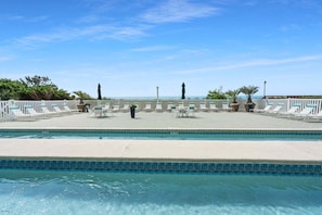 A pool area with lounge chairs, a table, and a view of the ocean. - Oceanfront 4BR condo with stunning views, pools, lazy river, and prime location near Main Street! (North Myrtle Beach)
