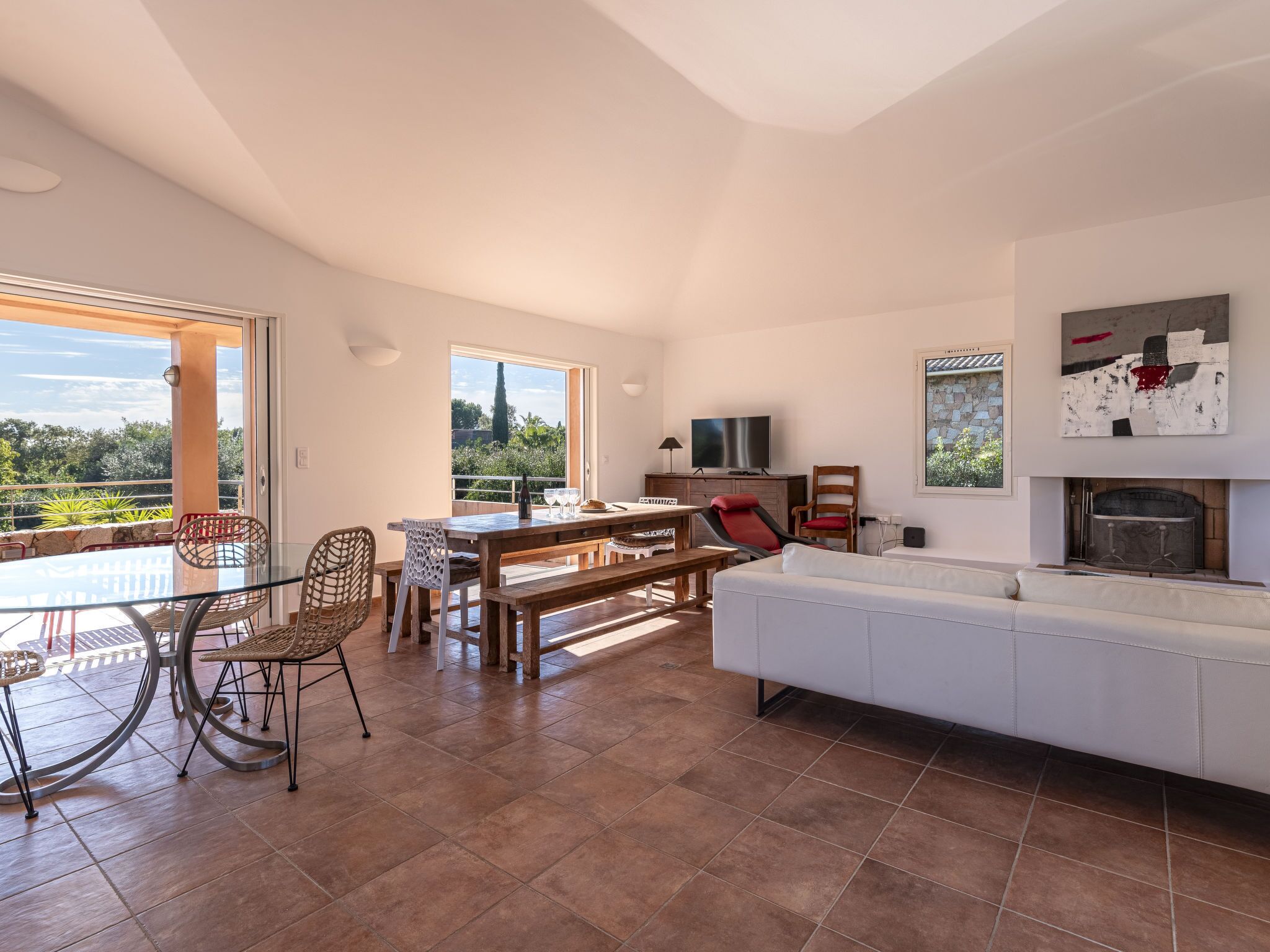 A spacious living area with a glass dining table, a sofa, and a fireplace.