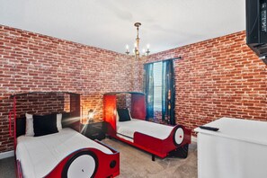 Ein Zimmer mit zwei Betten, einem weißen Schreibtisch und einer Ziegelwand.