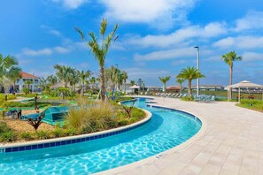 Ein Pool mit gebogener Form, umgeben von Palmen und Liegestühlen.