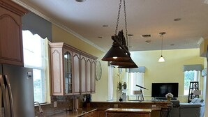 A spacious kitchen with wooden cabinets, a central island, stainless steel appliances, and a large window. - Wellington Hideaway Villa a spacious 5-bedroom house close to the Polo Club (Wellington)