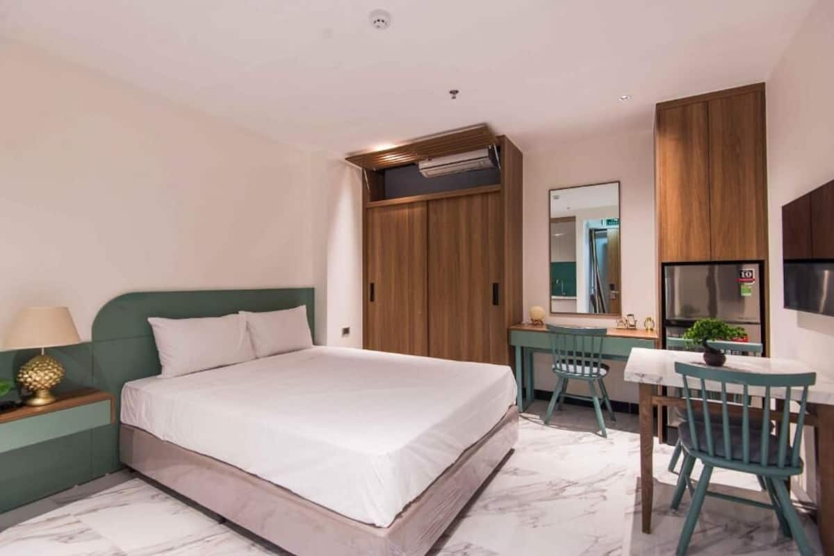 Une chambre d’hôtel comprenant un lit, un bureau, une chaise, un miroir et une armoire.