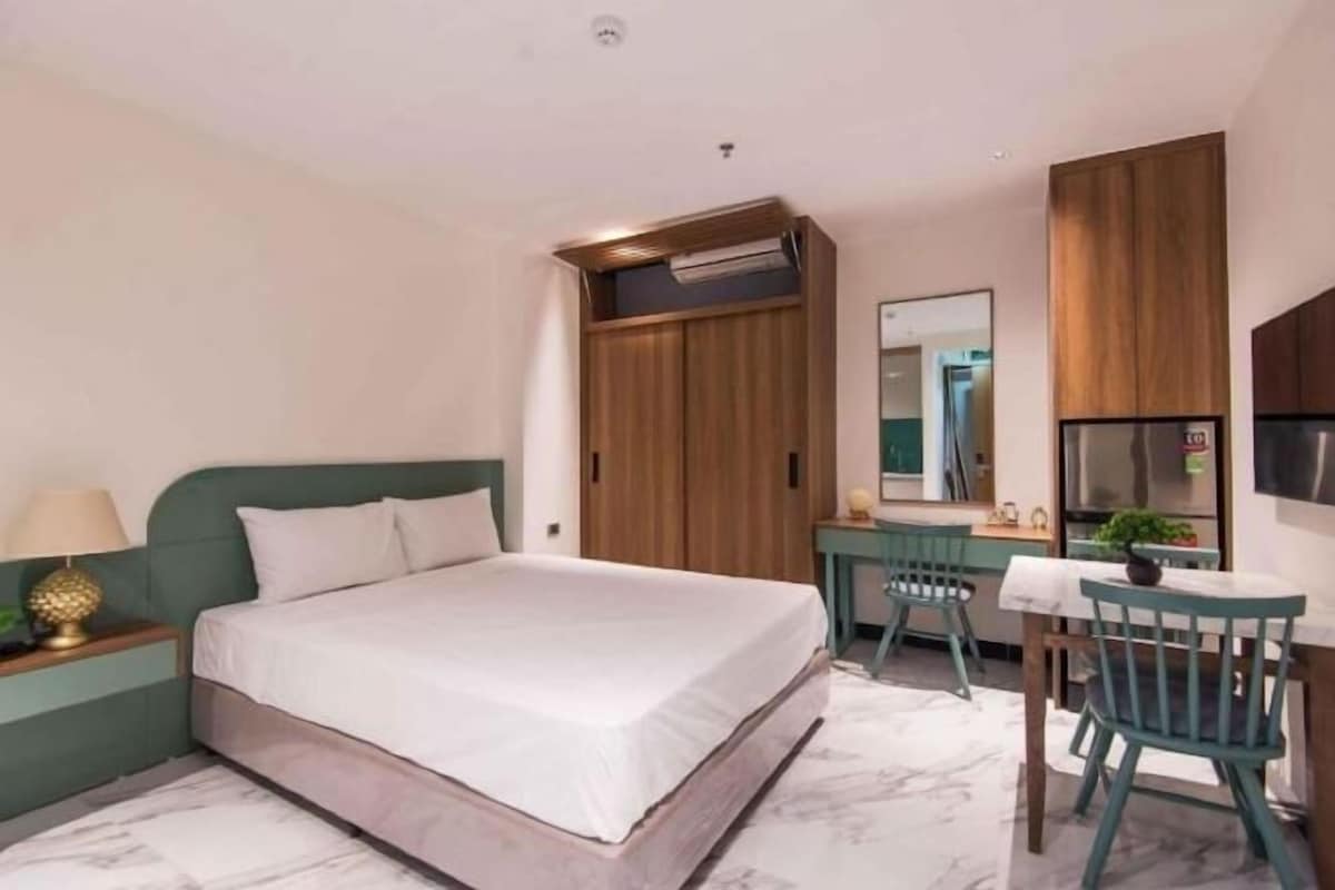 Un dormitorio con cama, escritorio, silla, espejo y armario.