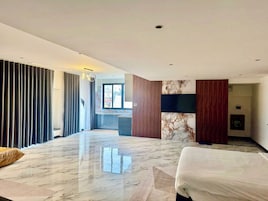 Quarto de hotel moderno com uma cama grande, televisão e vista para a cidade pela janela.