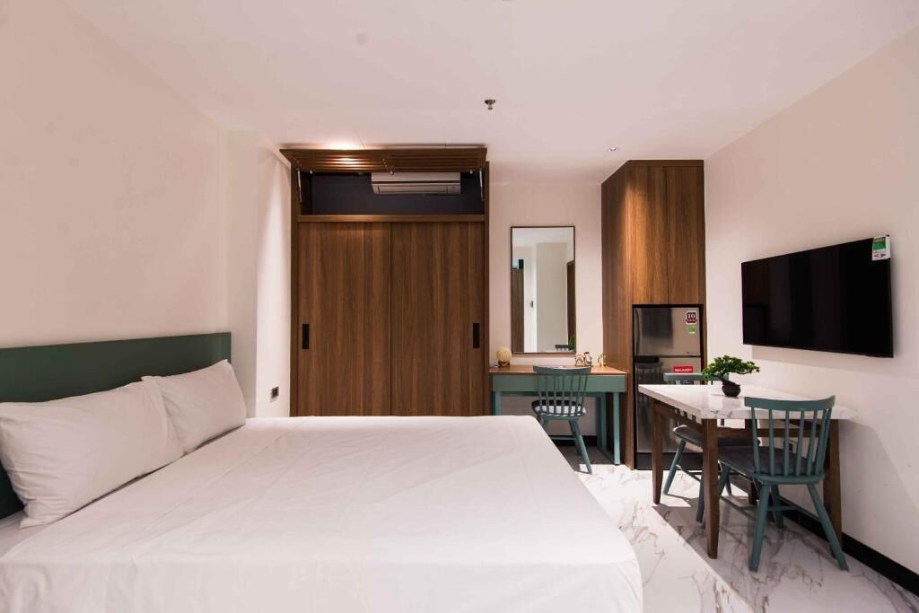 A hotel room with a bed, a desk, a chair, a TV, and a wardrobe.