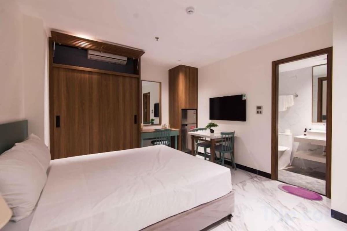 Een hotelkamer met een bed, een bureau, een stoel, een televisie en een badkamer.