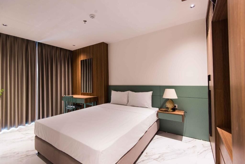 Et moderne hotelværelse med en stor seng, et skrivebord og et natbord med en lampe.