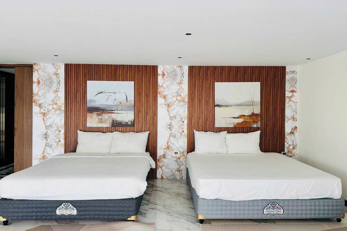 Une chambre double avec deux lits, des lambris en bois, des éléments décoratifs en marbre sur les murs et des œuvres d’art.