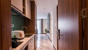 Un couloir étroit avec un coin cuisine d’un côté, comprenant un four à micro-ondes, une cuisinière et un évier.
