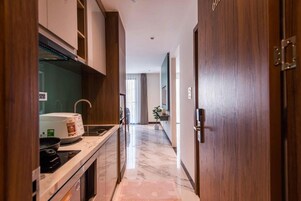 Corredor estreito com área de cozinha de um lado, incluindo micro-ondas, fogão e pia.