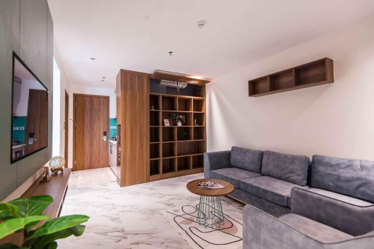 Un salon moderne avec un canapé gris, une table basse et une bibliothèque en bois.