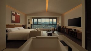 A spacious hotel room with a large bed, a seating area with a view, a flat-screen TV, and a bathtub.