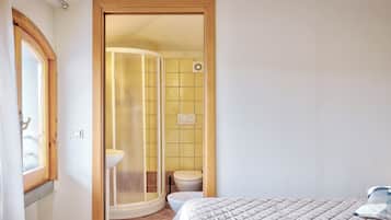 A bedroom with a bed, a bathroom with a shower, and a toilet.