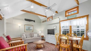 A cozy living room with a sofa, chairs, a dining table, and a TV.
