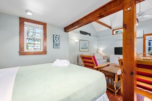 A bedroom with a bed, a desk, a chair, a television, and a window with a view of the outside. - Stay at The Salt Box - Steps from the Sea (South Yarmouth)