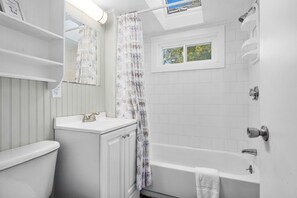 A bathroom with a toilet, sink, and bathtub. - Stay at The Salt Box - Steps from the Sea (South Yarmouth)