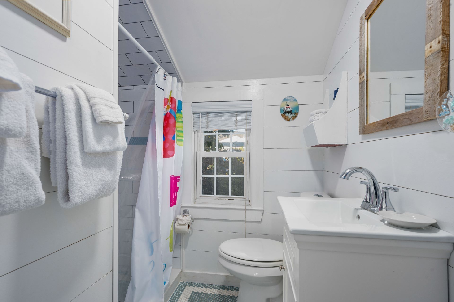 A small, white bathroom with a toilet, sink, and shower.