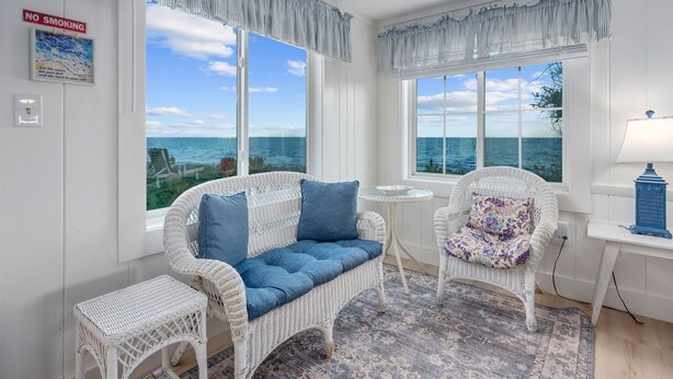 A room with wicker furniture, a view of the sea, and a 'No Smoking' sign.