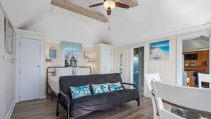A cozy room with a bed, a sofa, a dining table, and a kitchen area.