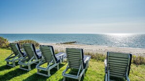 Een terras aan het strand met loungestoelen gericht op de zee.