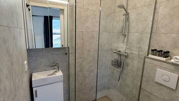 A modern bathroom with a glass shower enclosure, a white sink, and a toilet.