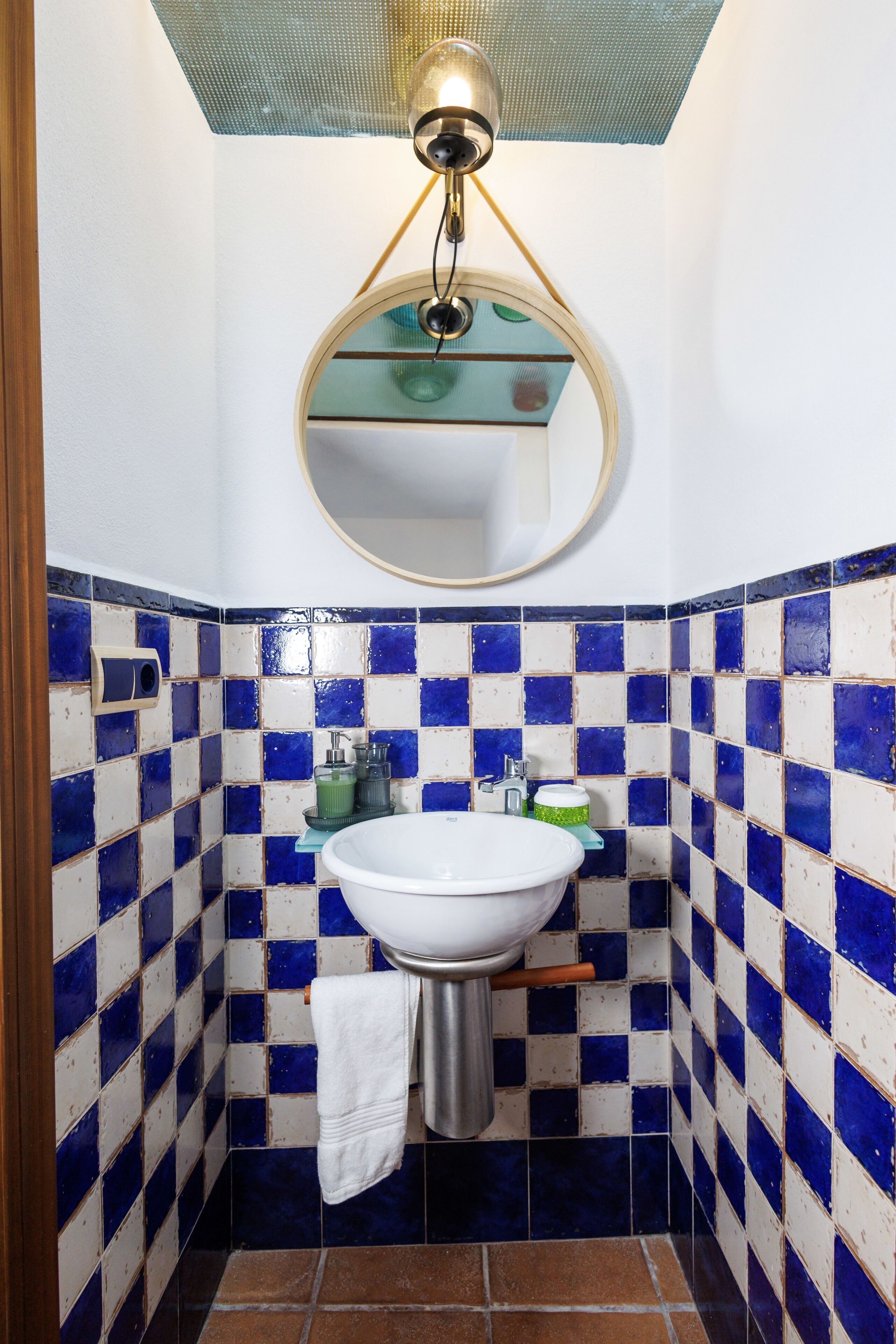 A bathroom with a white sink, blue and white tiles, a mirror, and a towel hanging on the wall.