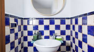 A bathroom with a white sink, blue and white tiles, a mirror, and a towel hanging on the wall.