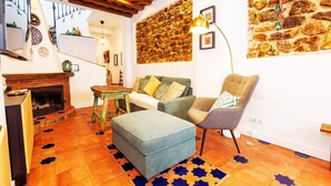 A living room with a fireplace, a stone wall, a sofa, a chair, and a patterned rug.