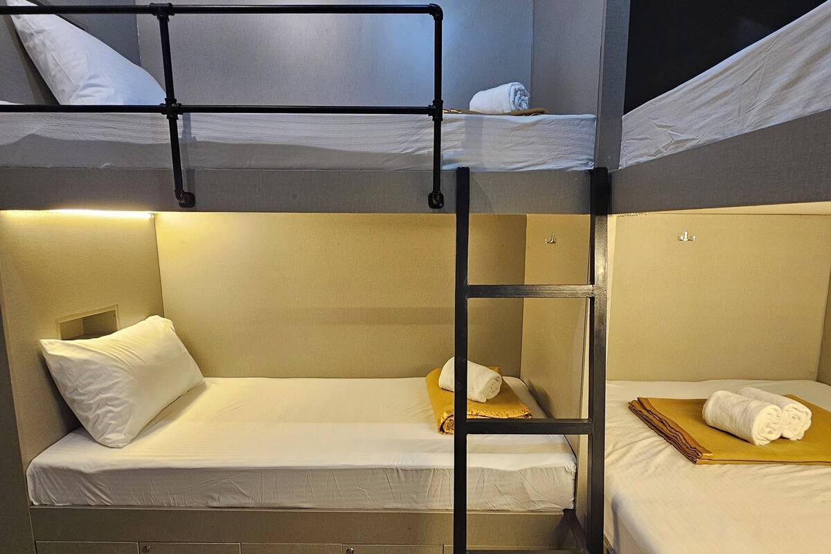 A bunk bed room with a ladder, a small table, and a pillow.