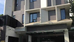 Un edificio moderno con entrada a un garaje, un letrero que indica dos plazas de estacionamiento disponibles y un coche estacionado adentro.