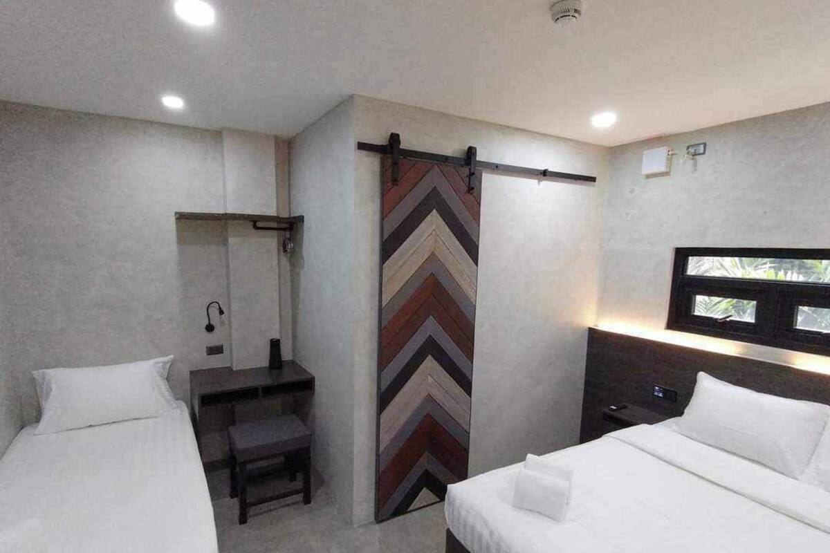 A hotel room with two beds, a shower, and a large window.