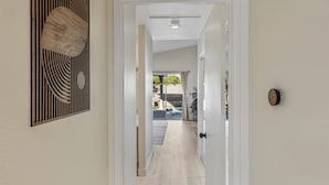 A hallway with a wooden floor, a door with a round handle, and a wall-mounted decorative panel.