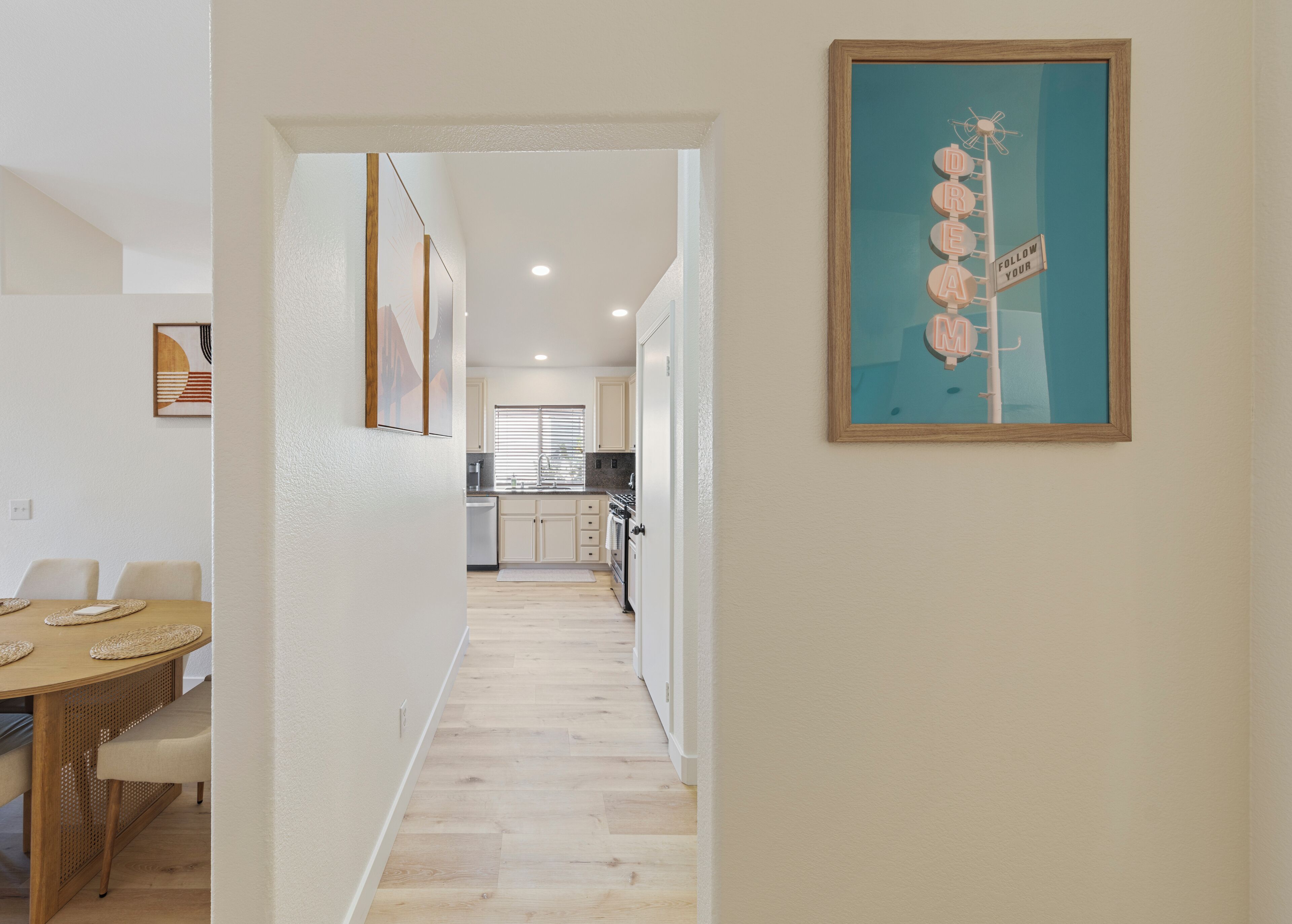 A modern kitchen with white cabinets, a built-in oven, and a window with blinds.