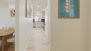A modern kitchen with white cabinets, a built-in oven, and a window with blinds.