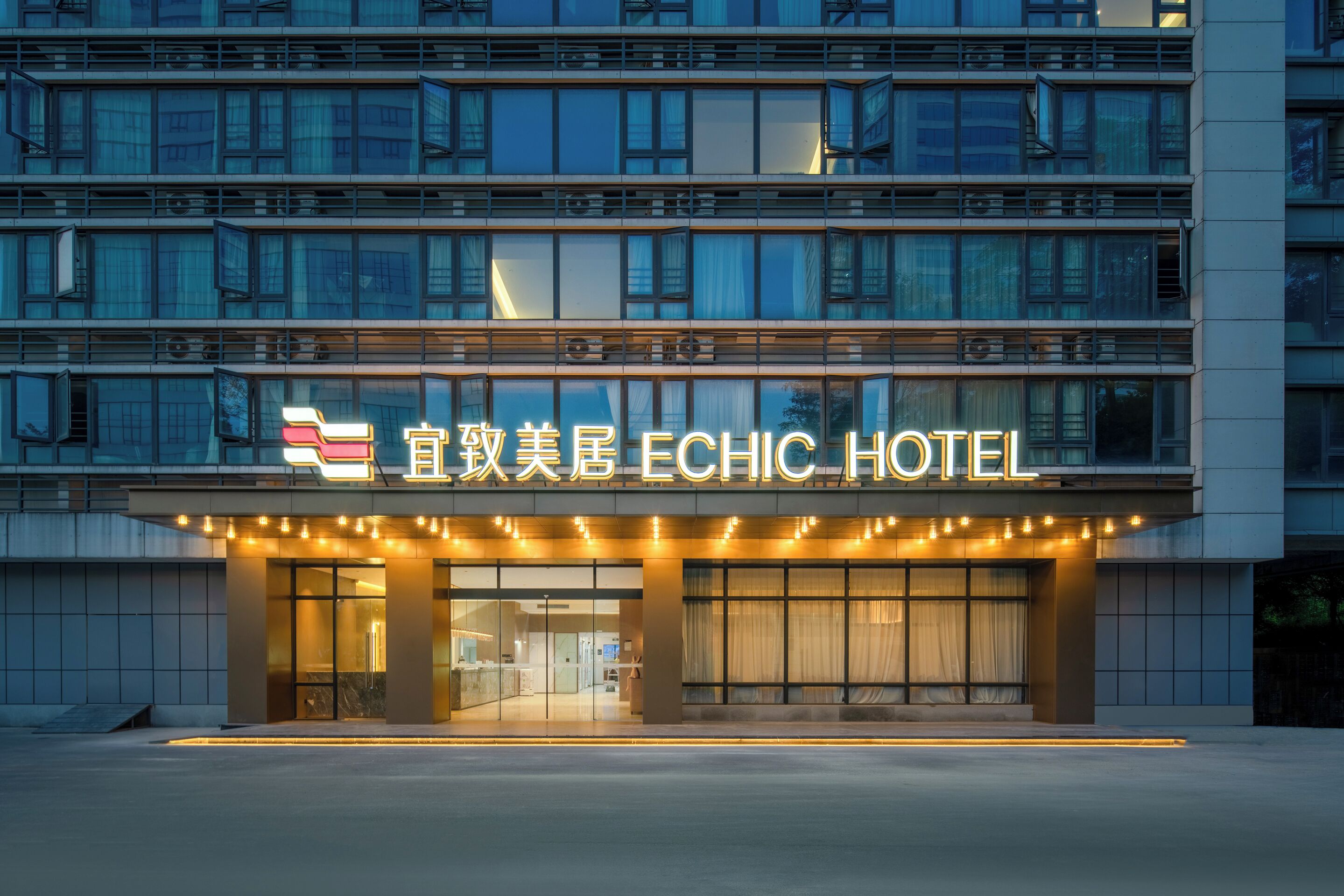 Fachada moderna de hotel con señalización iluminada, amplias ventanas y un diseño contemporáneo y limpio.