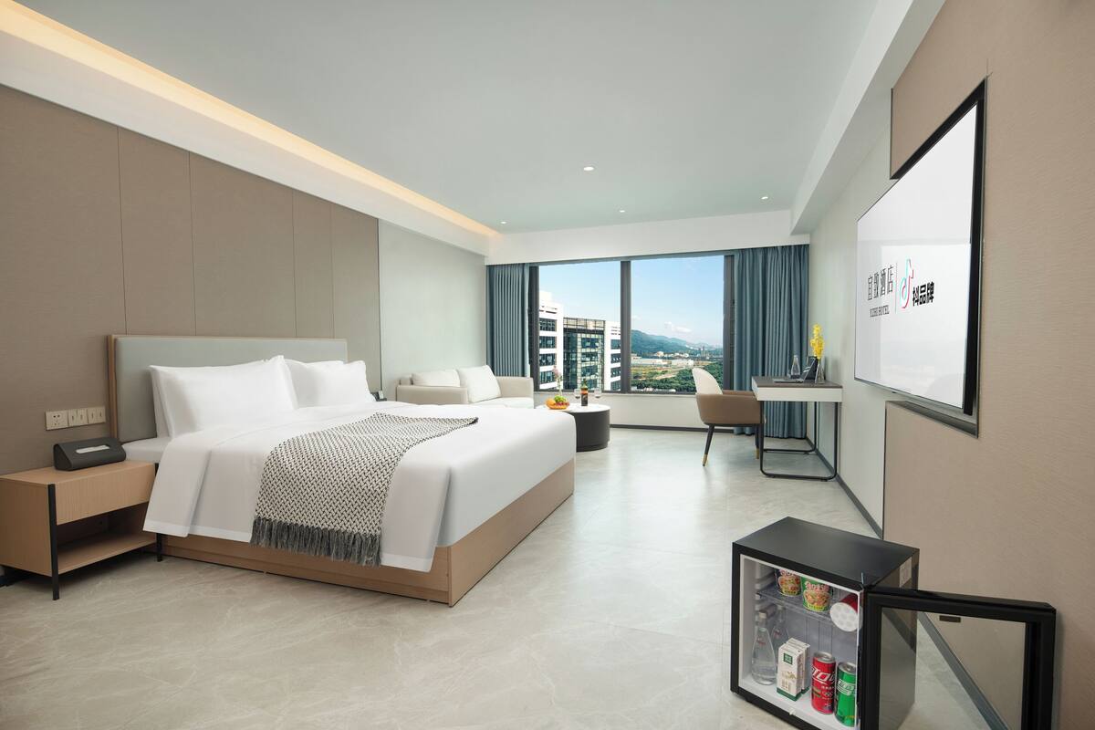 Una habitación de hotel moderna con una cama grande, un escritorio y vistas a la ciudad.